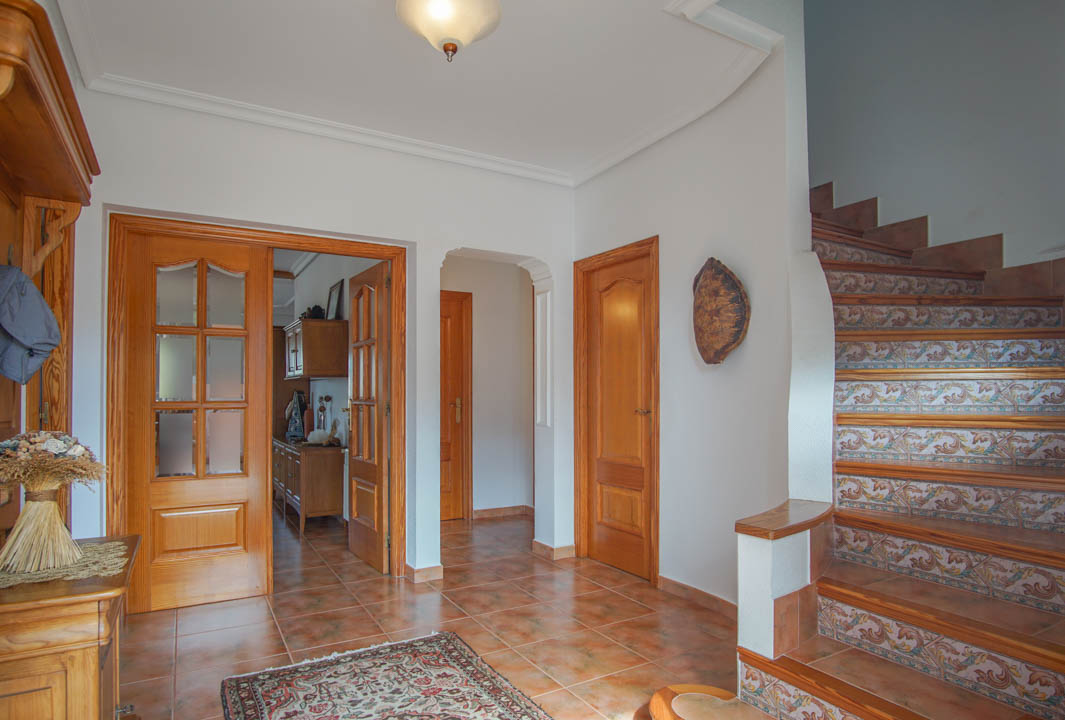 Hall de entrada con suelos de gres, puertas de madera maciza y una escalera decorada con azulejos tradicionales que conecta las plantas.