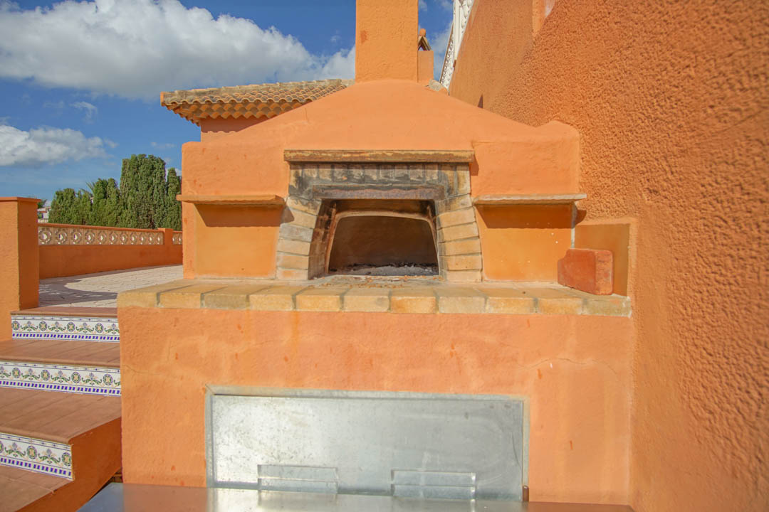 Horno de leña tradicional integrado en la terraza exterior, con arco de ladrillo visto y detalles de azulejos decorativos en las escaleras laterales.