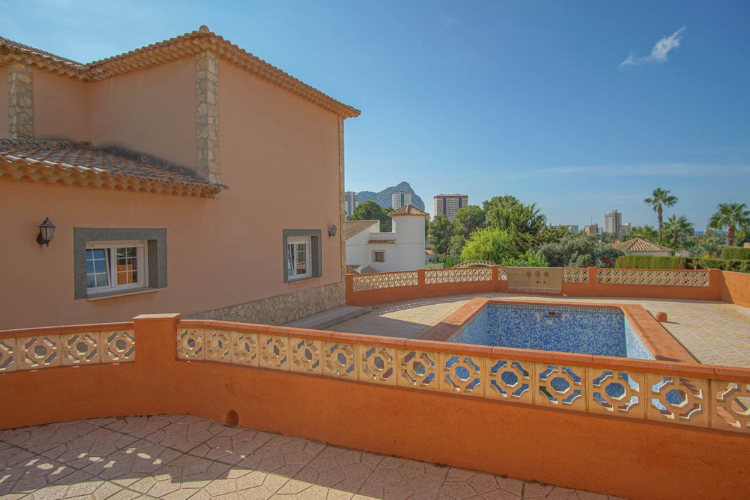 Terraza elevada con piscina privada y balaustrada decorativa, ofreciendo vistas despejadas hacia el Peñón de Ifach y el entorno urbano.