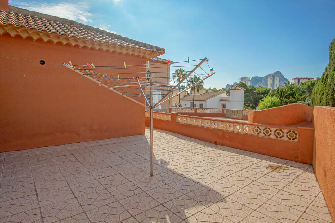 Terraza solárium con suelo de gres decorativo y muros en tono terracota, ofreciendo vistas despejadas hacia el Peñón de Ifach y el entorno residencial.