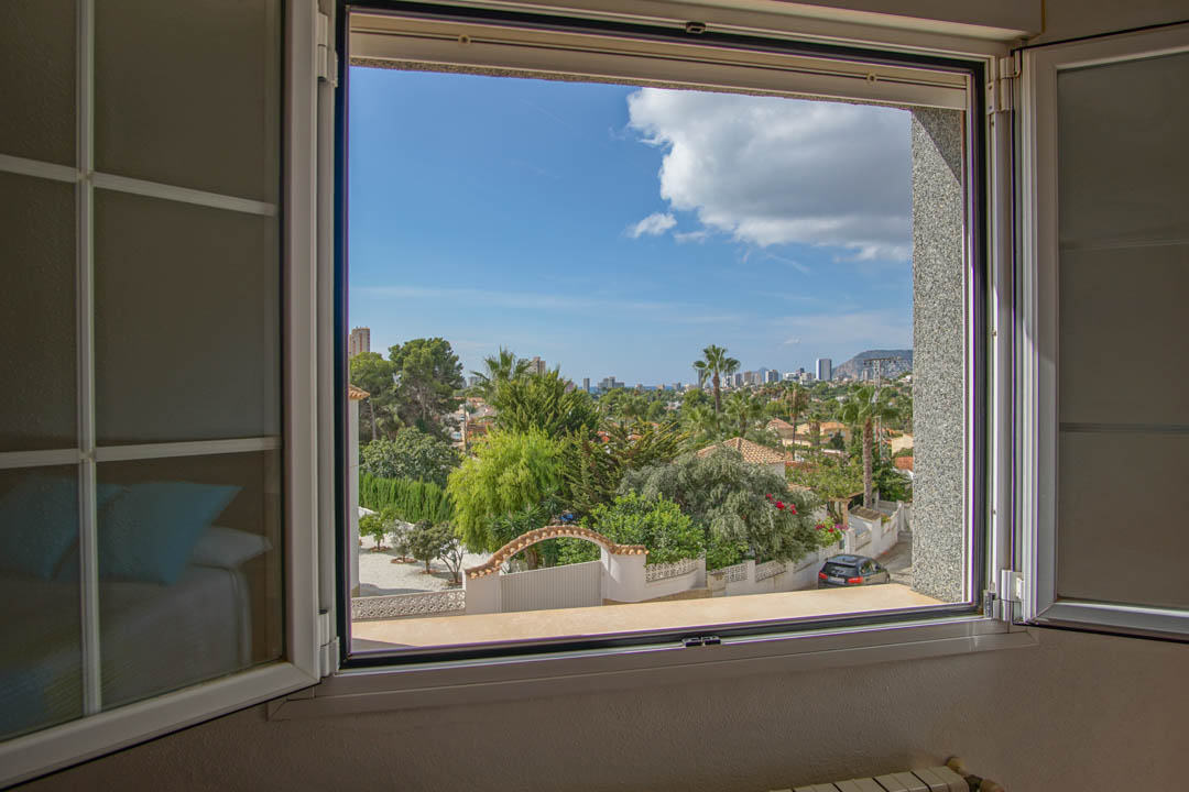 Vista despejada desde la planta superior que muestra el entorno residencial arbolado y el horizonte urbano bajo la luz natural del día.