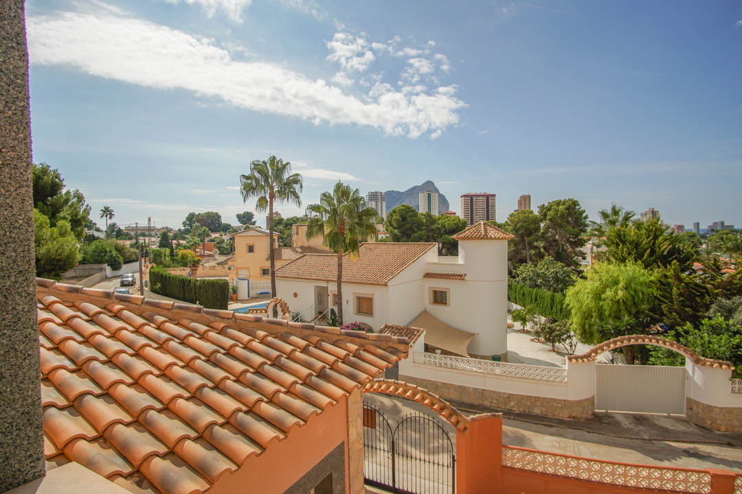 Vista elevada desde la propiedad que destaca los tejados de teja tradicional, el entorno residencial con palmeras y la silueta del Peñón de Ifach al fondo.