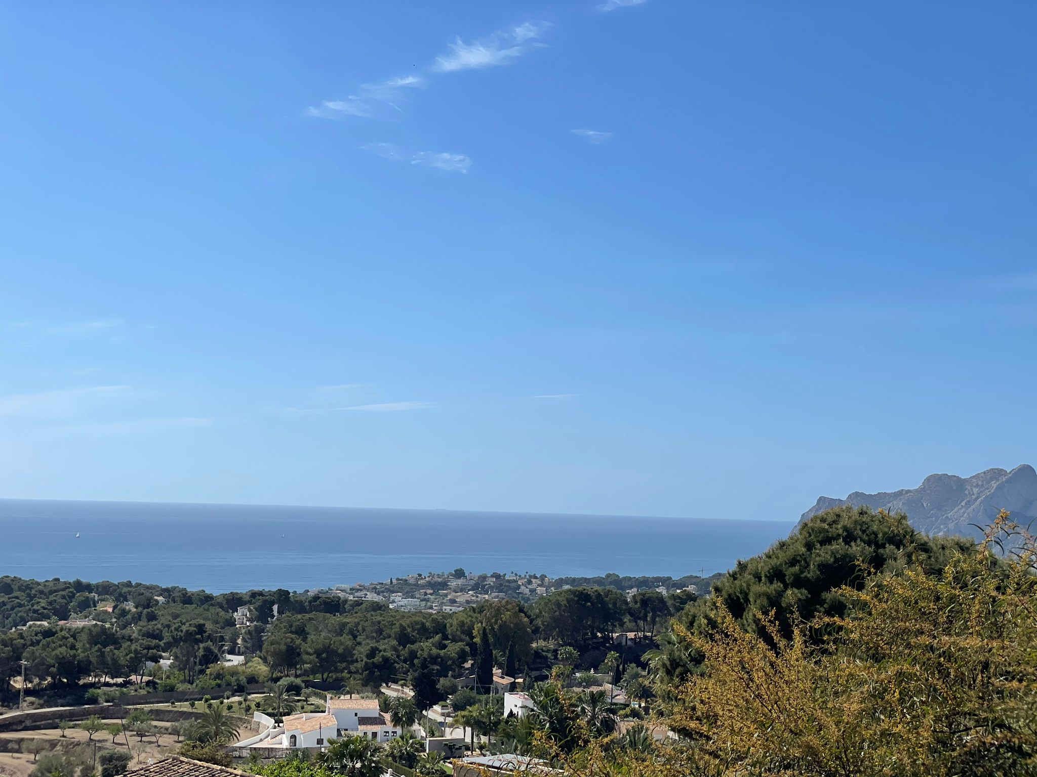 Vista panorámica desde la propiedad hacia la costa de Benissa, mostrando la densa vegetación mediterránea y el mar bajo un cielo despejado.