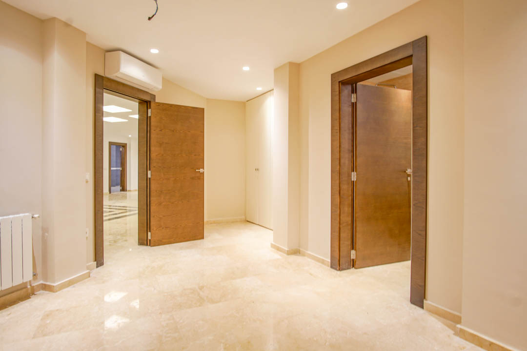 Distribuidor con suelos de mármol pulido, puertas de madera noble con marcos oscuros e iluminación empotrada. Incluye climatización individual y armarios integrados blancos.
