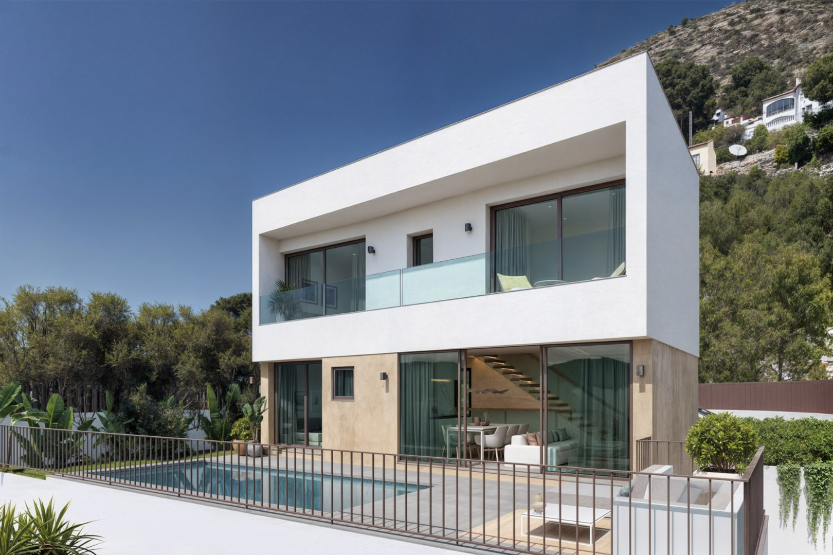 Fachada moderna de dos niveles con piscina privada, terraza de gres y amplios ventanales que integran el salón y la escalera interior con el entorno natural.