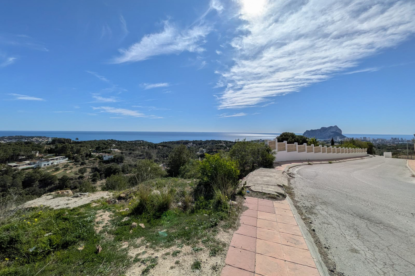 Vista panorámica desde la calle de acceso, destacando la costa de Benissa, el mar Mediterráneo y la silueta del Peñón de Ifach en el horizonte.
