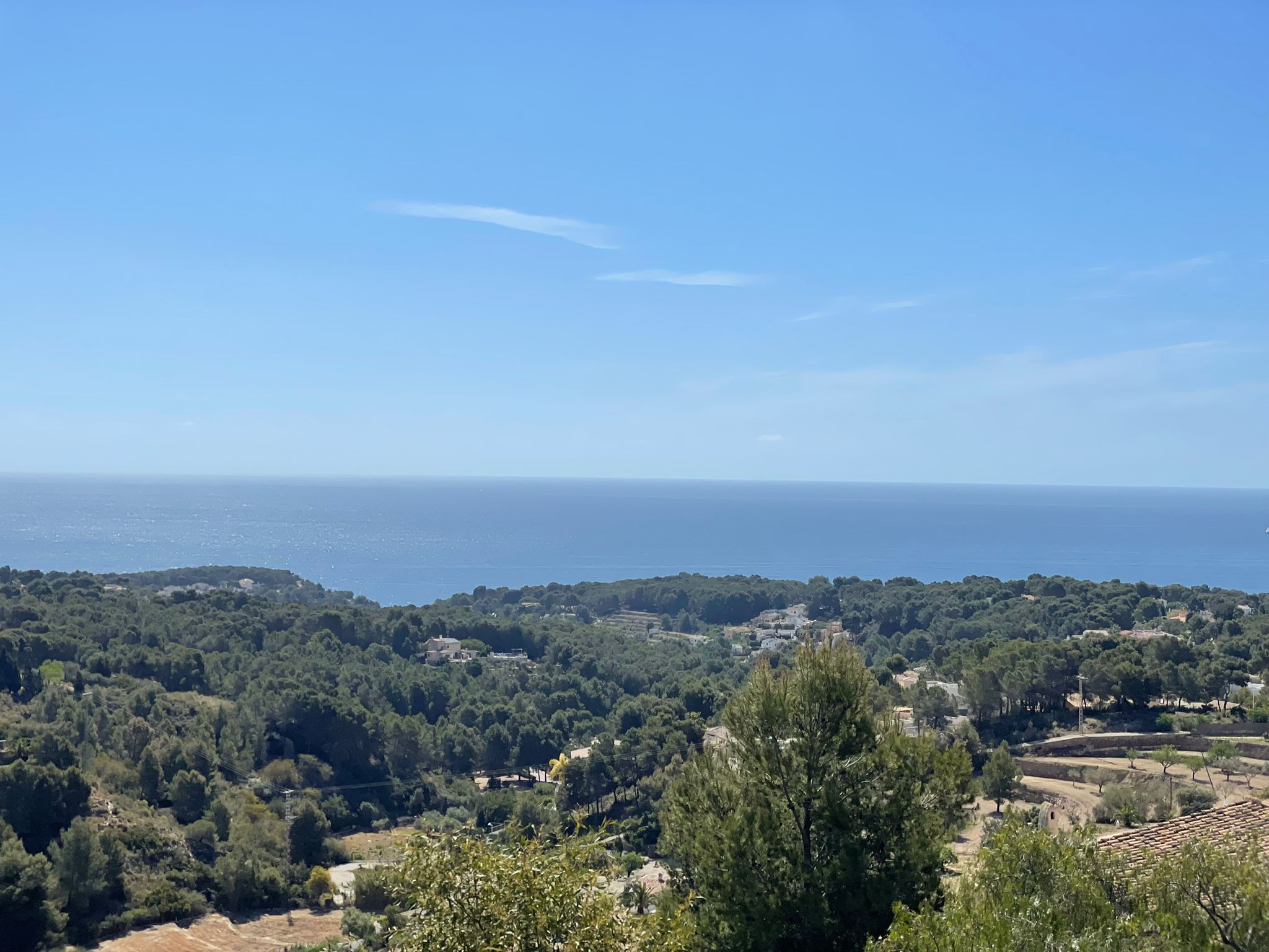 Vista panorámica desde la parcela hacia el mar Mediterráneo, destacando la densa vegetación de pinos y el relieve abancalado característico de Benissa.