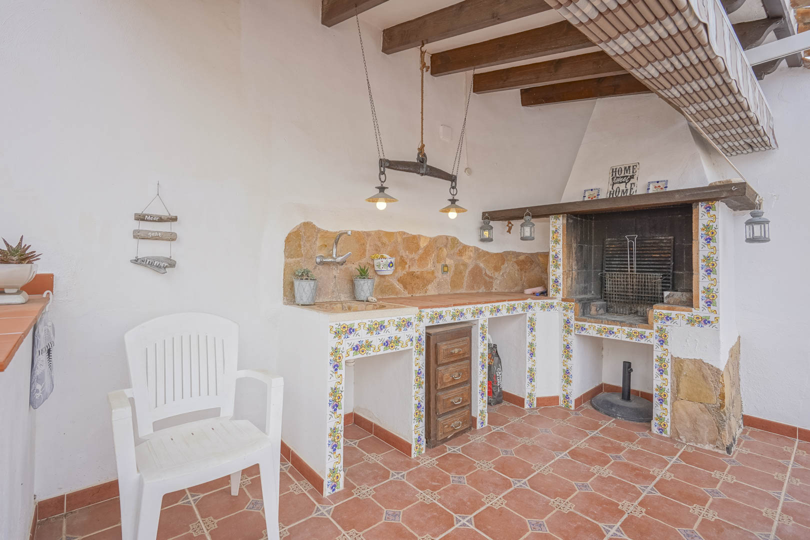 Barbacoa exterior con encimera de piedra y azulejos decorativos en villa de estilo castellano.