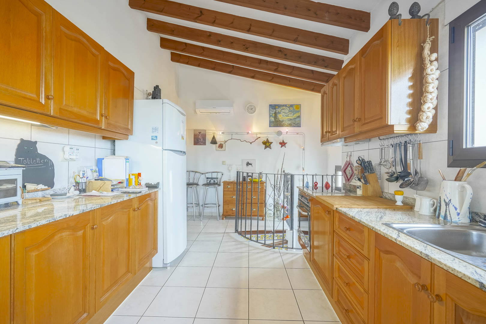 Cocina americana con vigas de madera, muebles de madera y encimera de granito.