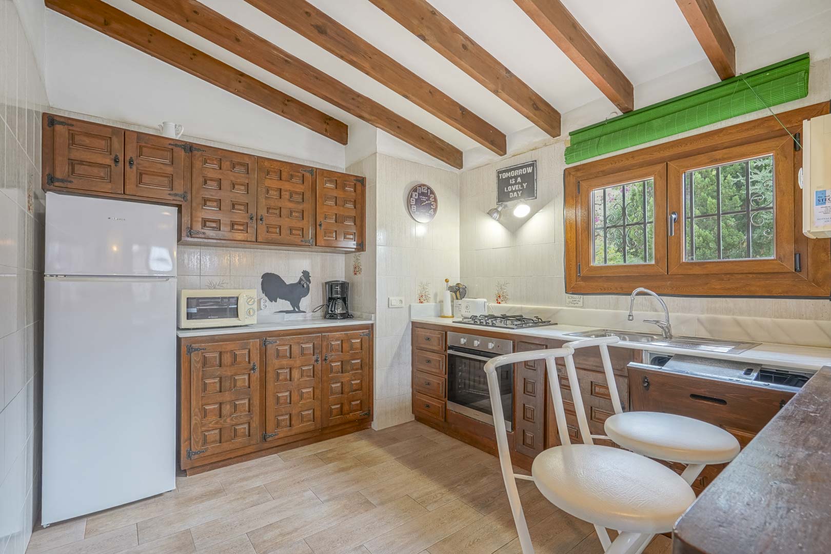 Cocina rústica con vigas de madera, armarios de madera tallada y electrodomésticos modernos.