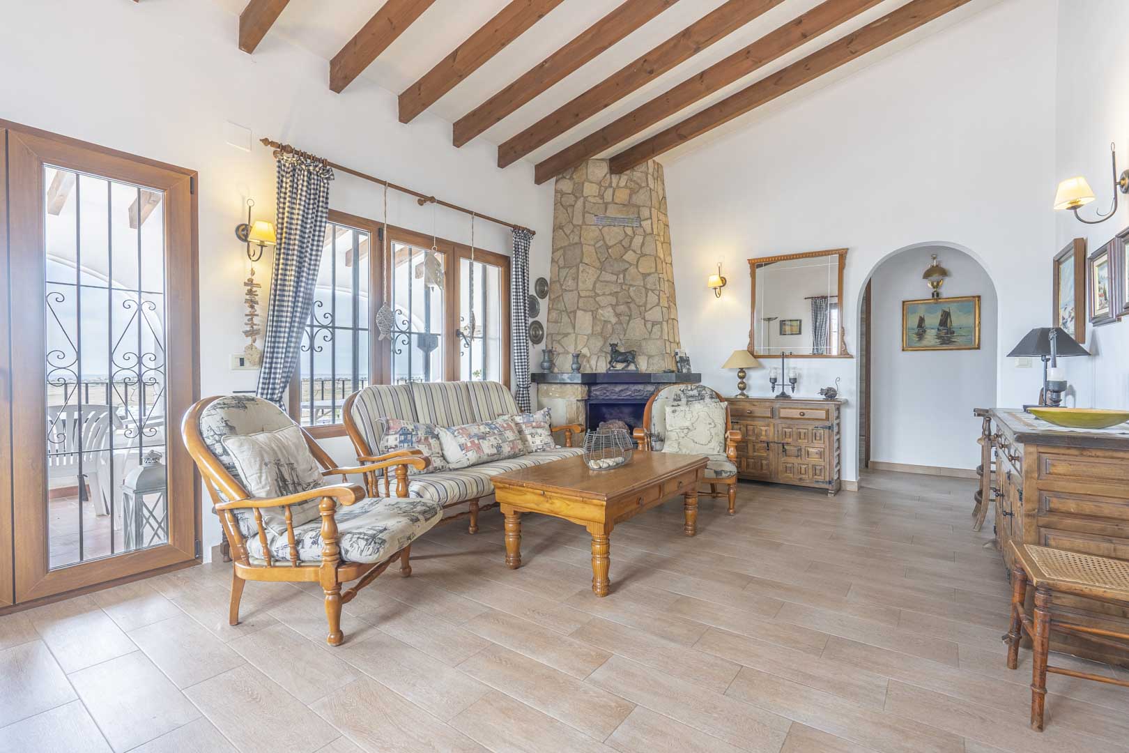 Salón con chimenea de piedra, vigas de madera y muebles de estilo rústico.