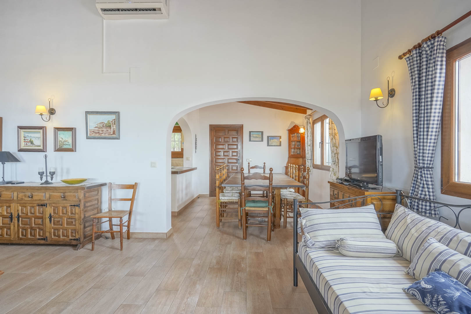 Salón con suelo de cerámica, arcos que dan al comedor y muebles rústicos de madera.