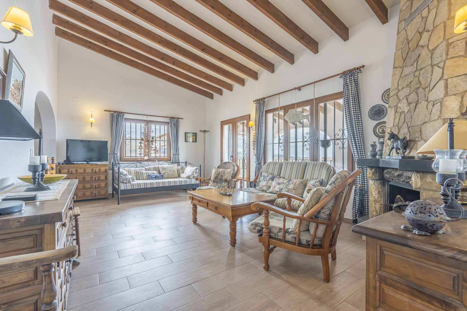 Salón con vigas de madera, chimenea de piedra y muebles rústicos.