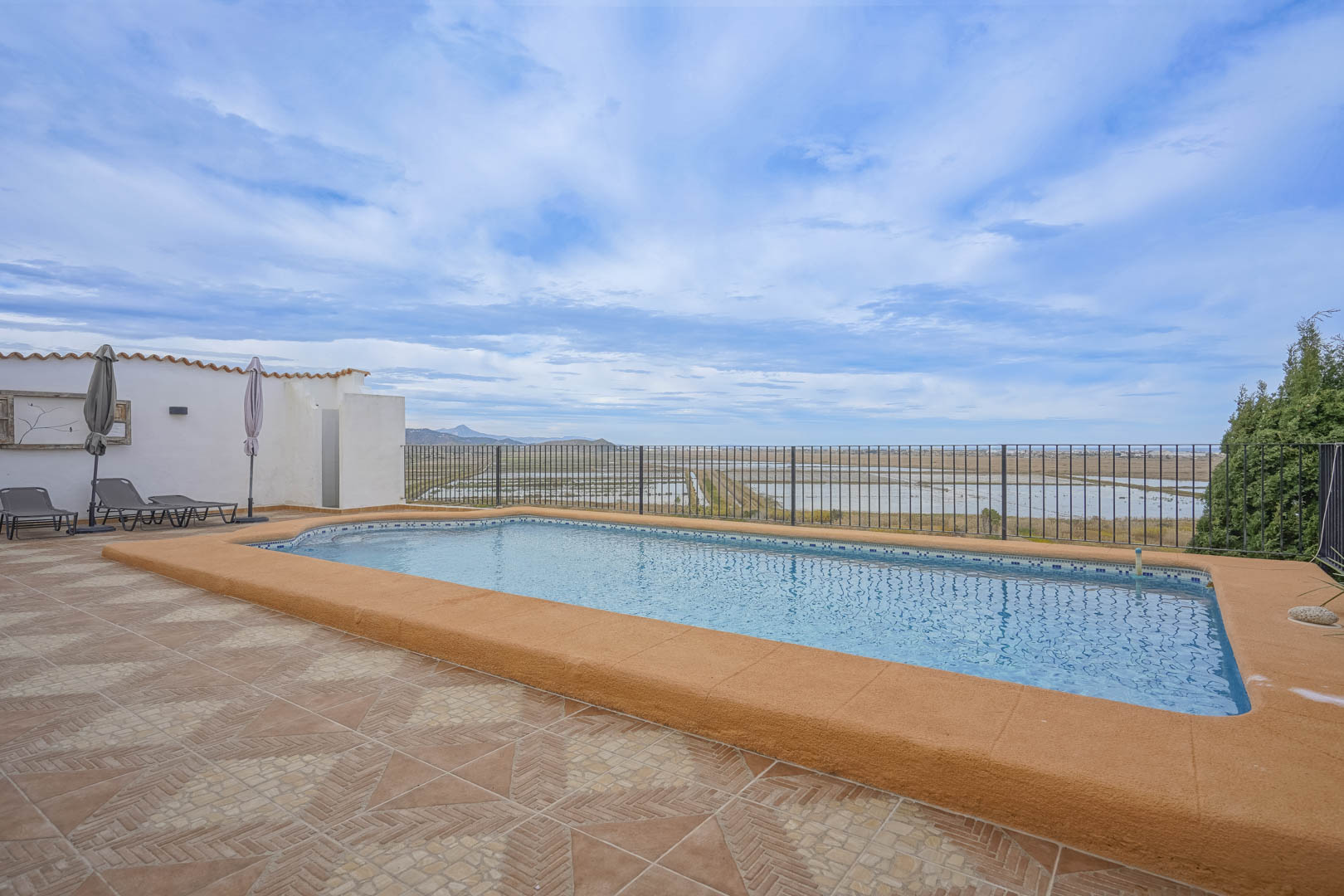 Vista de la piscina con borde color albero y baldosas de terracota, con vistas a la reserva natural.