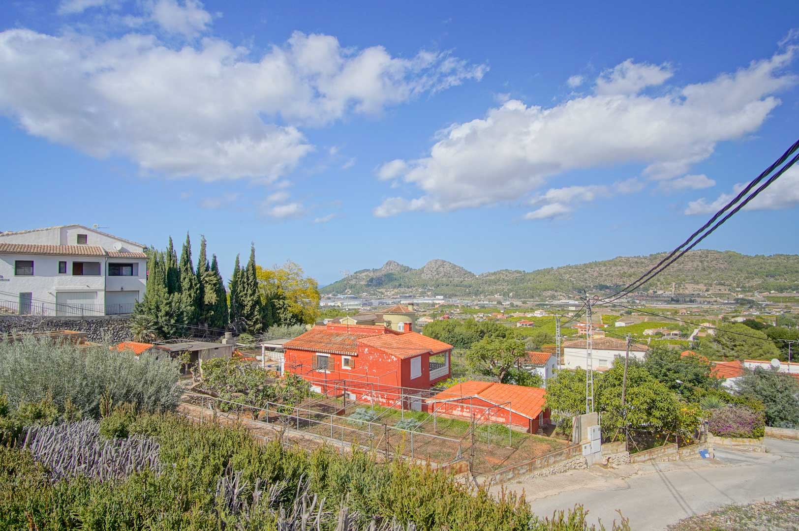 Vista panorámica desde la propiedad hacia el valle y las montañas de Pedreguer, destacando la vegetación mediterránea y el entorno residencial tranquilo bajo un cielo despejado.