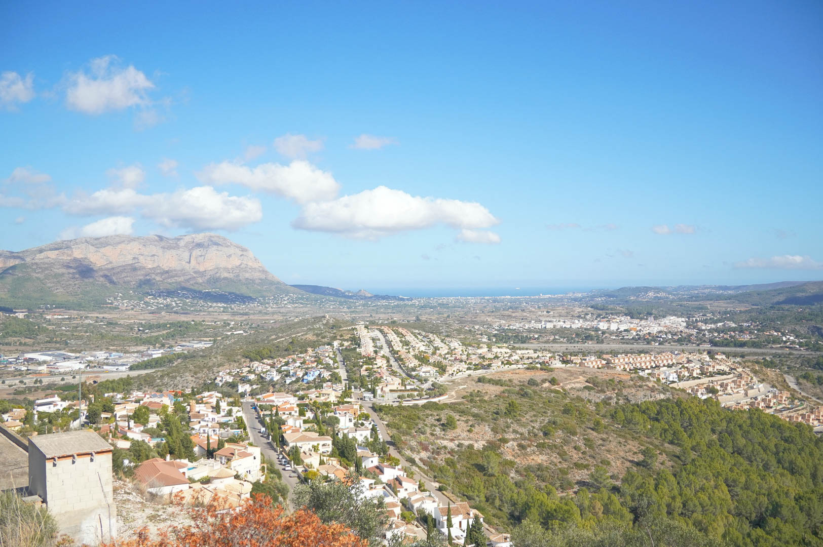 Vistas panorámicas del valle de Pedreguer y el macizo del Montgó, con el mar Mediterráneo perfilándose en el horizonte bajo un cielo despejado.