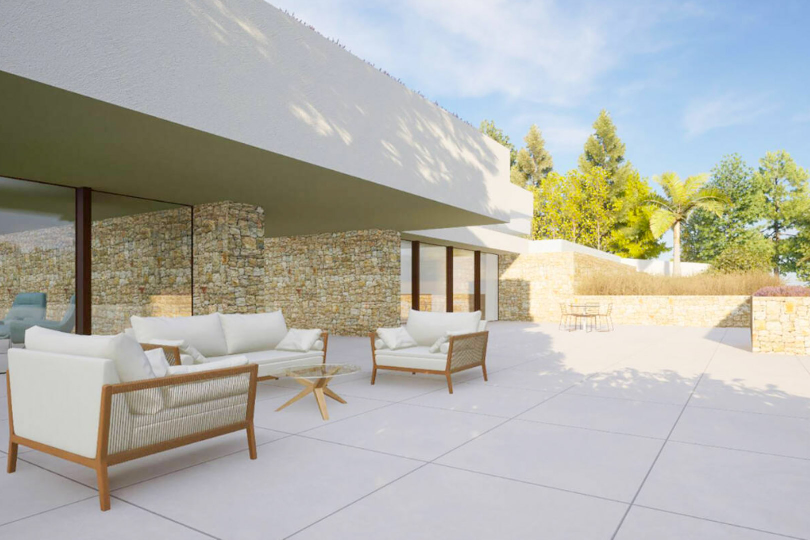 Terraza exterior con mobiliario de diseño, paredes de piedra natural y amplios ventanales que integran el interior con el jardín mediterráneo.