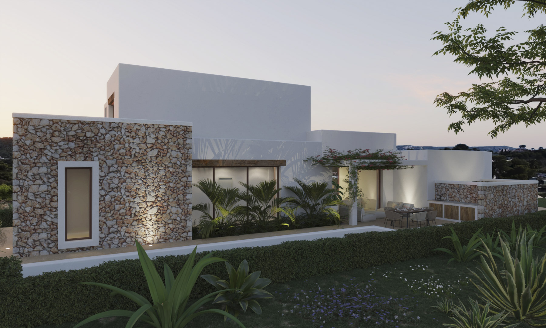 Fachada de estilo ibicenco que combina muros de piedra natural con volúmenes blancos, destacando la terraza exterior con zona de comedor y vegetación mediterránea.
