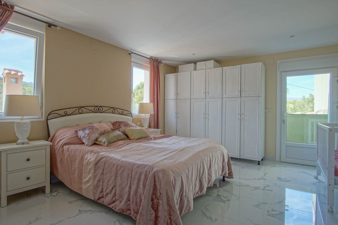 Dormitorio con suelos de gres efecto mármol, amplios armarios blancos y salida directa a una terraza con vistas al entorno natural.