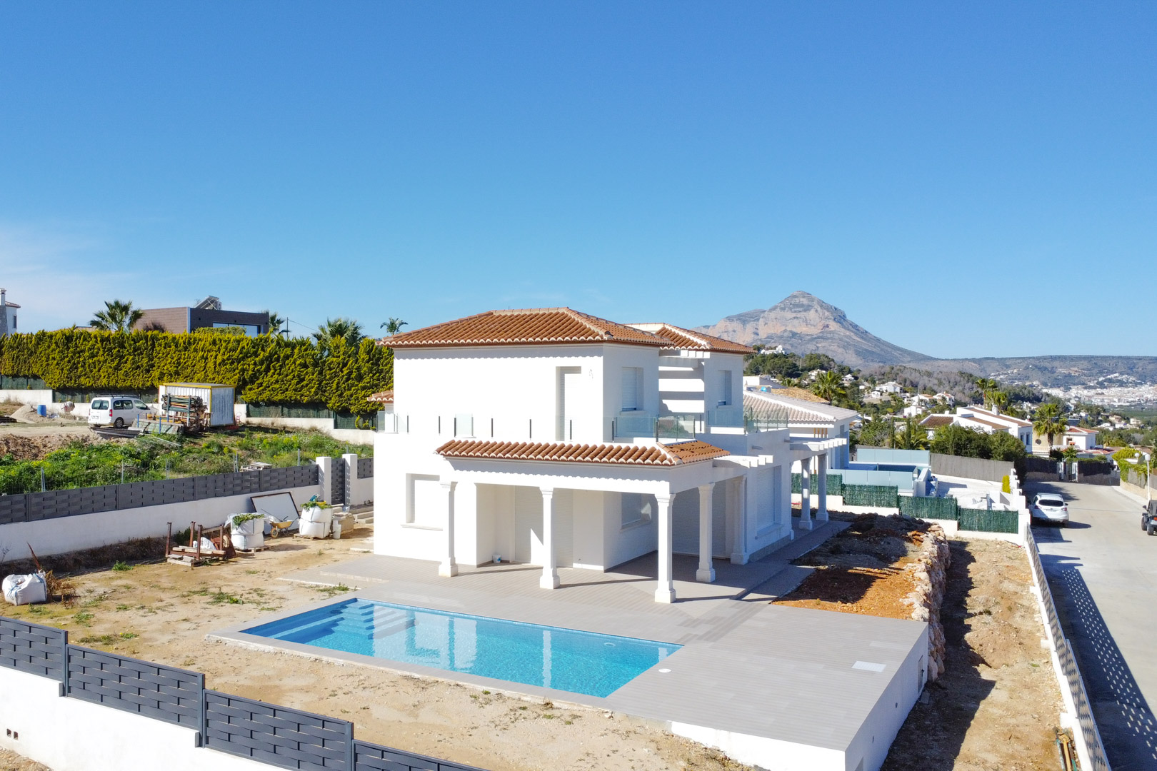 Vista exterior elevada del chalet con su piscina rectangular, amplia terraza de gres y el emblemático Montgó destacando en el horizonte de Jávea.