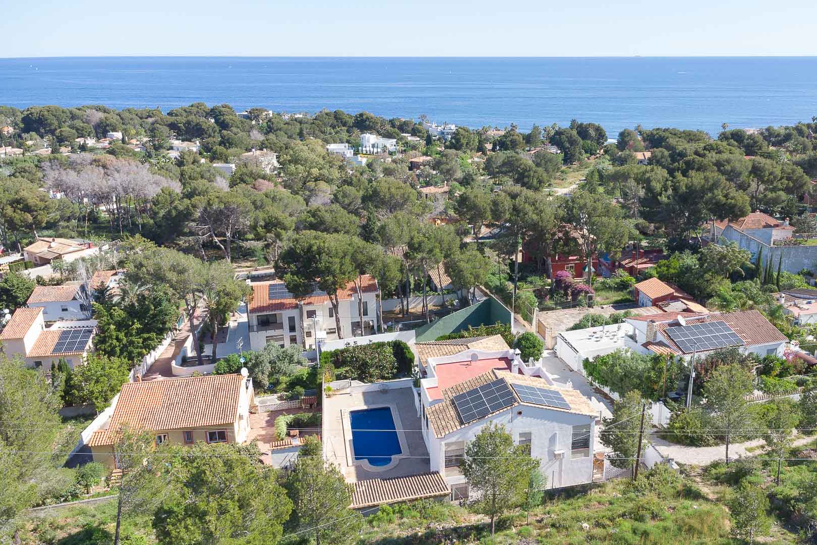 Vista aérea de la propiedad en Las Rotas, destacando la piscina privada, paneles solares y su integración en un entorno boscoso con vistas al mar Mediterráneo.