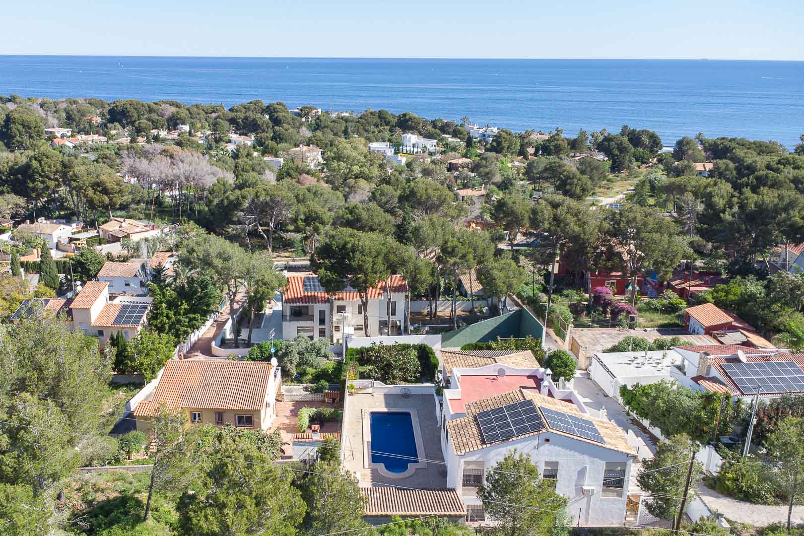 Vista aérea de la villa en Las Rotas, destacando su piscina privada, paneles solares y el entorno boscoso con vistas al mar Mediterráneo.
