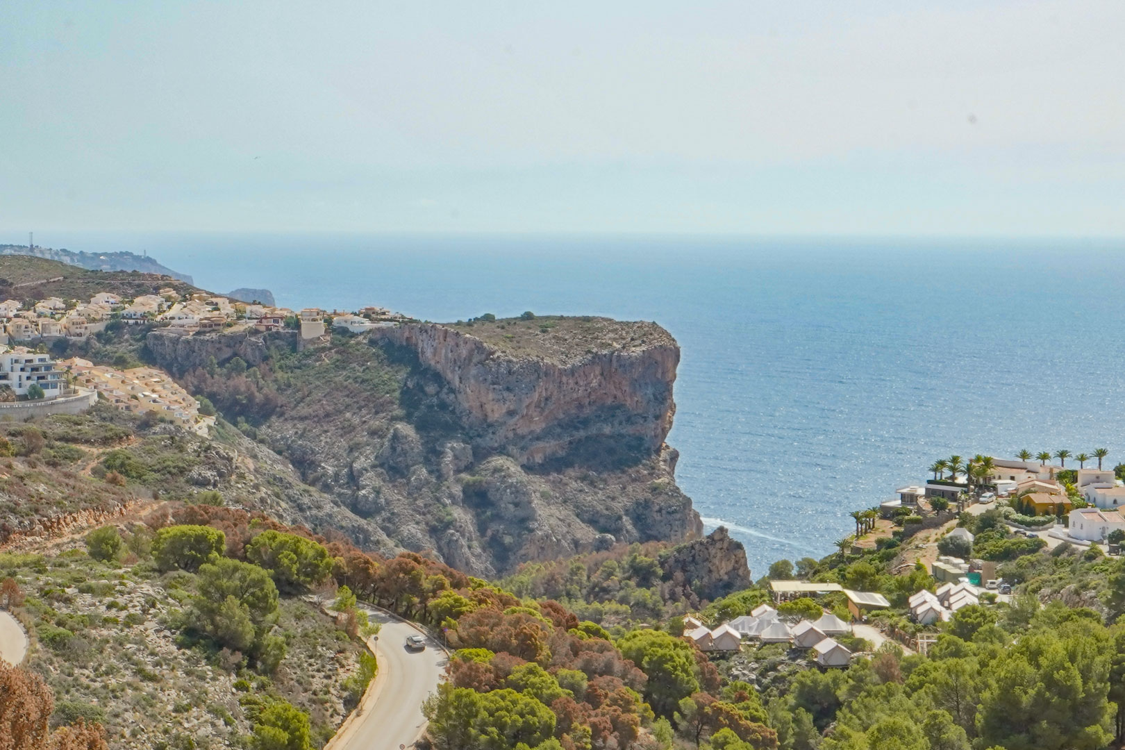 Vista panorámica desde Cumbre del Sol hacia los acantilados y el mar Mediterráneo, con la carretera costera serpenteando entre la vegetación local.