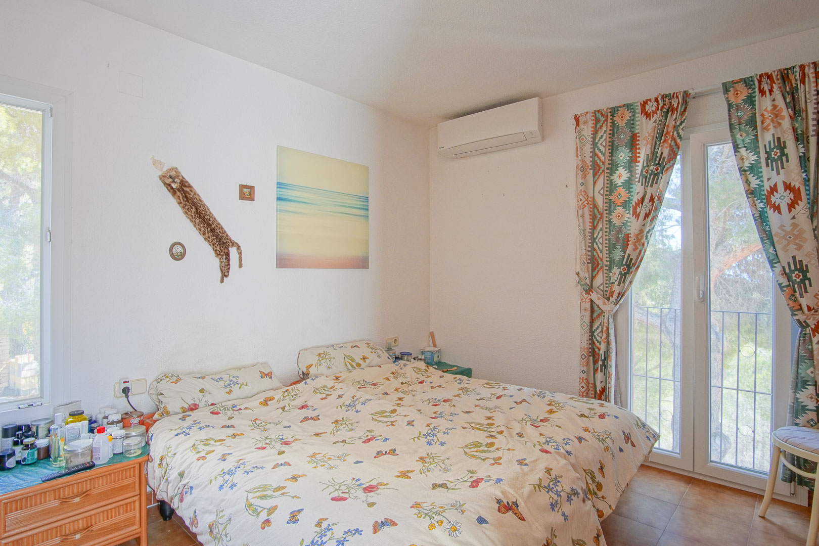 Dormitorio luminoso con aire acondicionado, acceso directo a la terraza mediante ventanal y suelos de gres de estilo rústico.