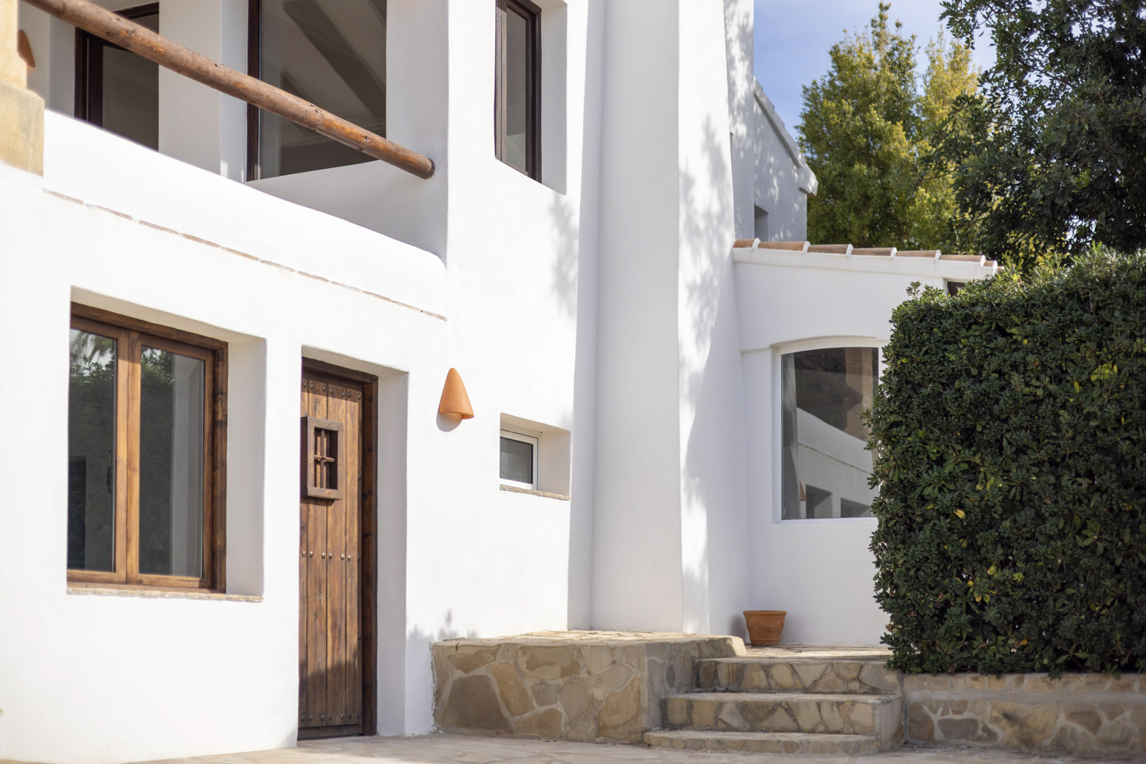 Fachada de villa en Jávea con detalles rústicos: puerta de madera, muros blancos y escalones de piedra.