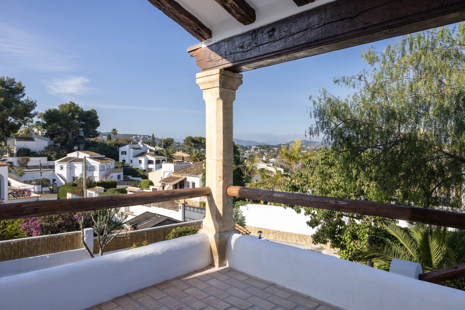 Terraza con vistas en Tosalet, Jávea. Detalles rústicos: vigas de madera y suelo de baldosas.
