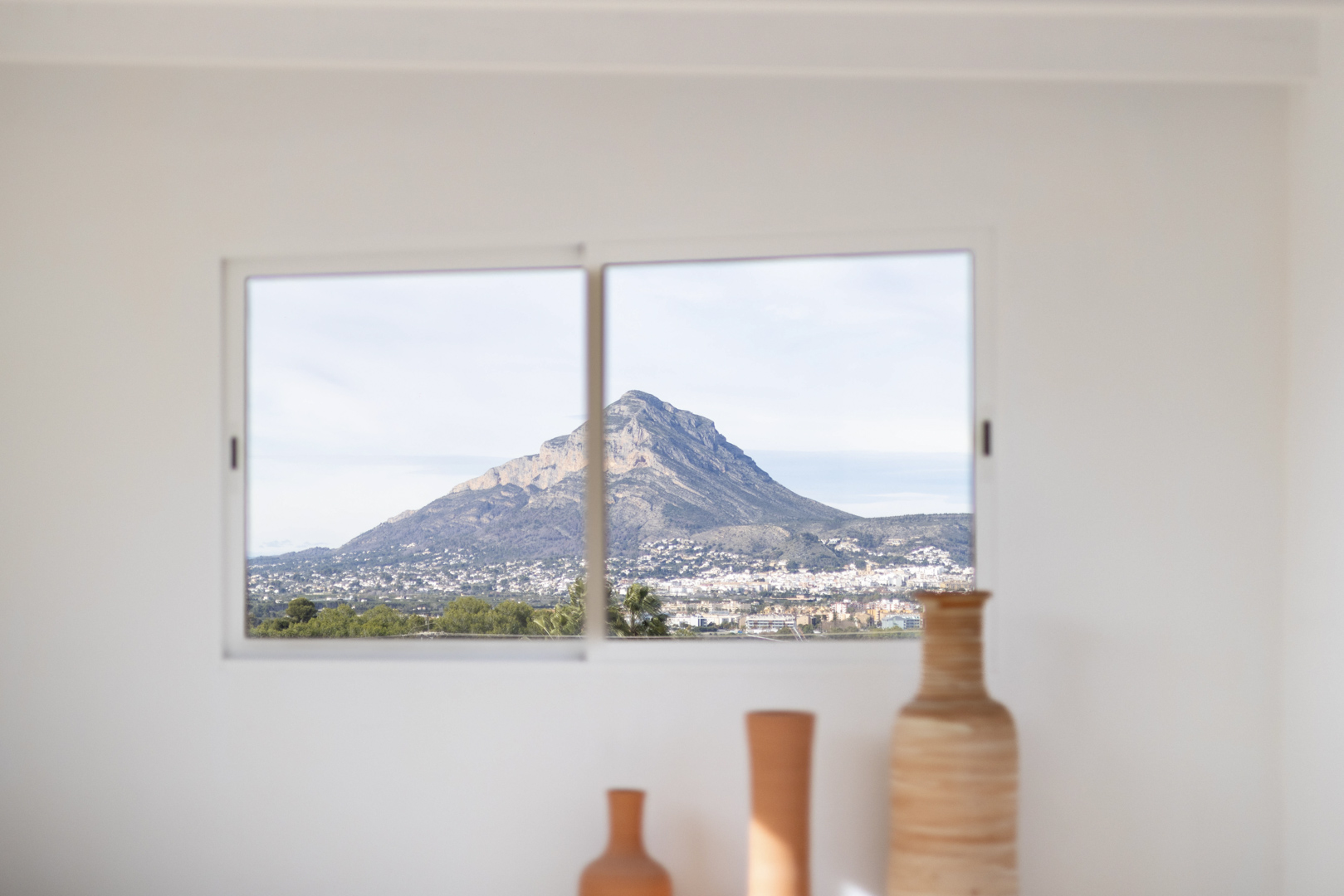 Vista desde el interior con jarrones de cerámica y ventana con vistas a la montaña.