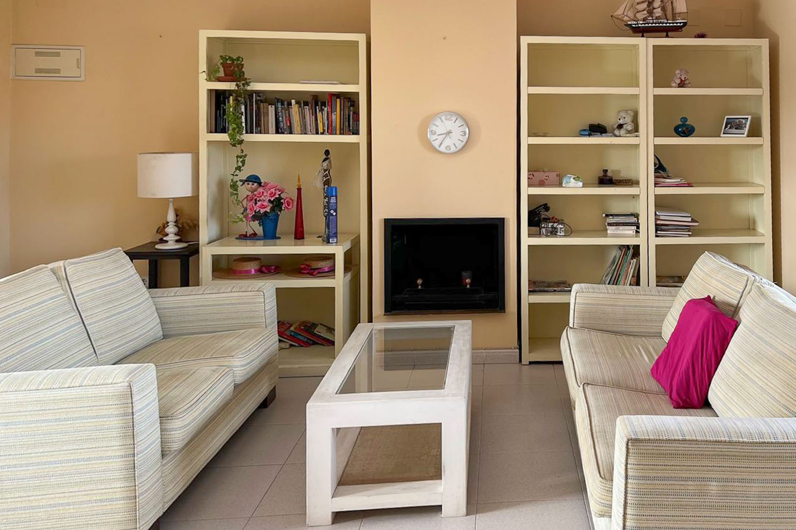 Salón con sofás a rayas, estanterías de obra y chimenea decorativa.