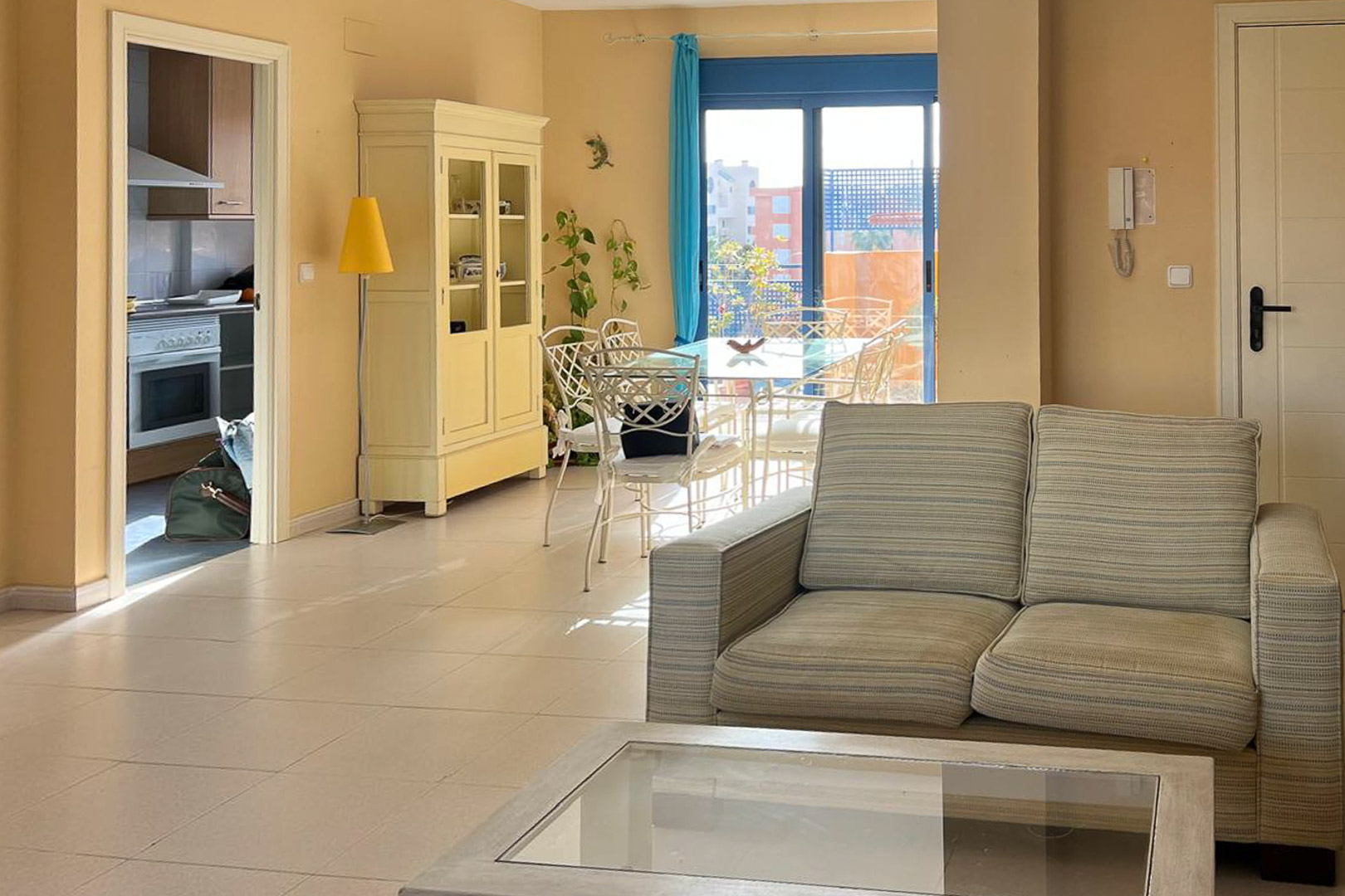 Salón luminoso con sofá tapizado, mesa de centro y acceso a terraza.