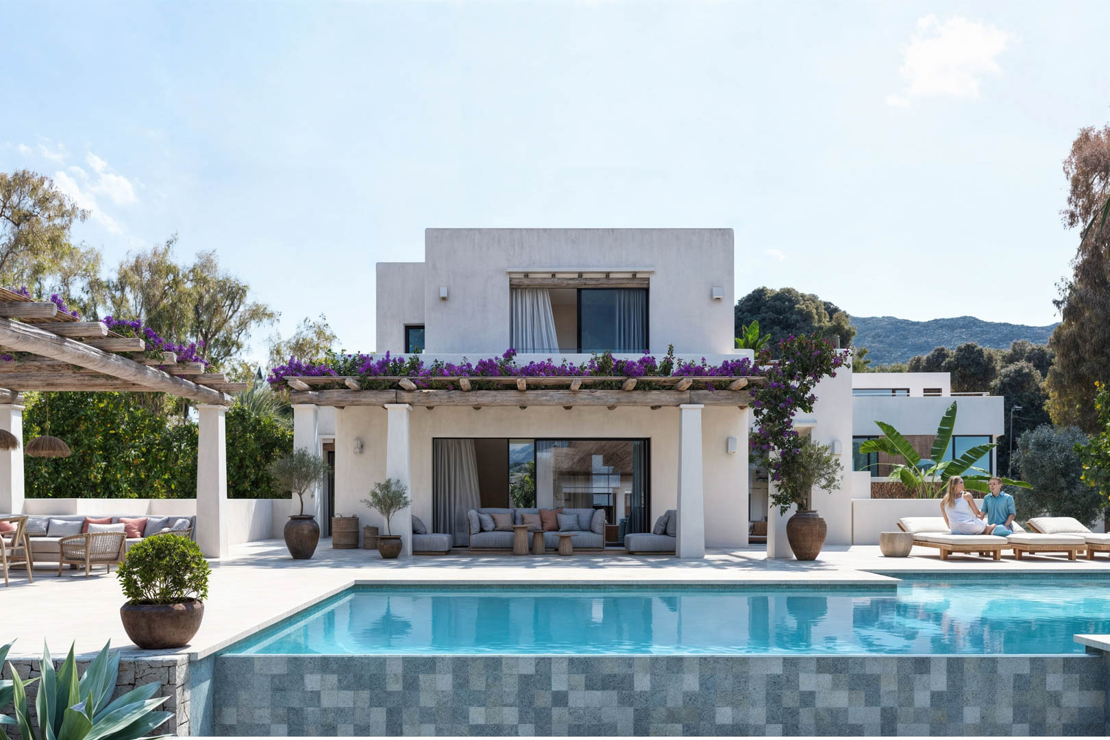 Vista exterior de la villa con piscina de mosaico, pérgola de madera con glicinas y fachada blanca.