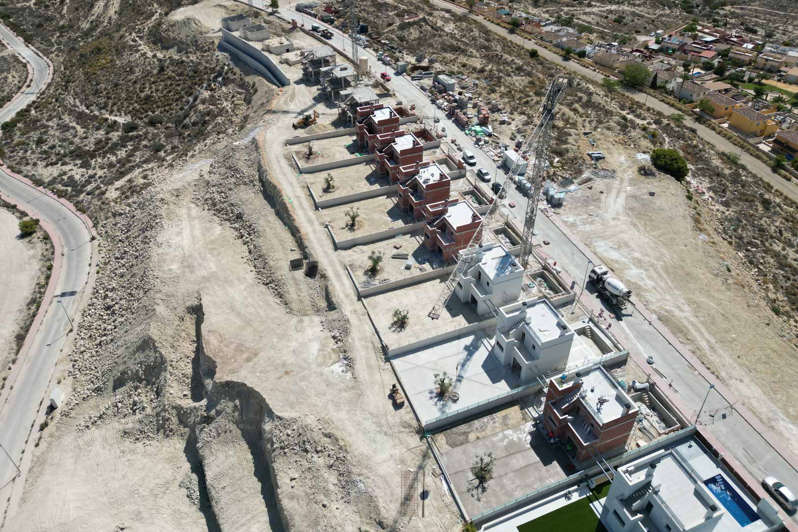 Vista aérea del complejo de villas en fase de construcción, situadas en una zona elevada con parcelas individuales y estructuras arquitectónicas contemporáneas.