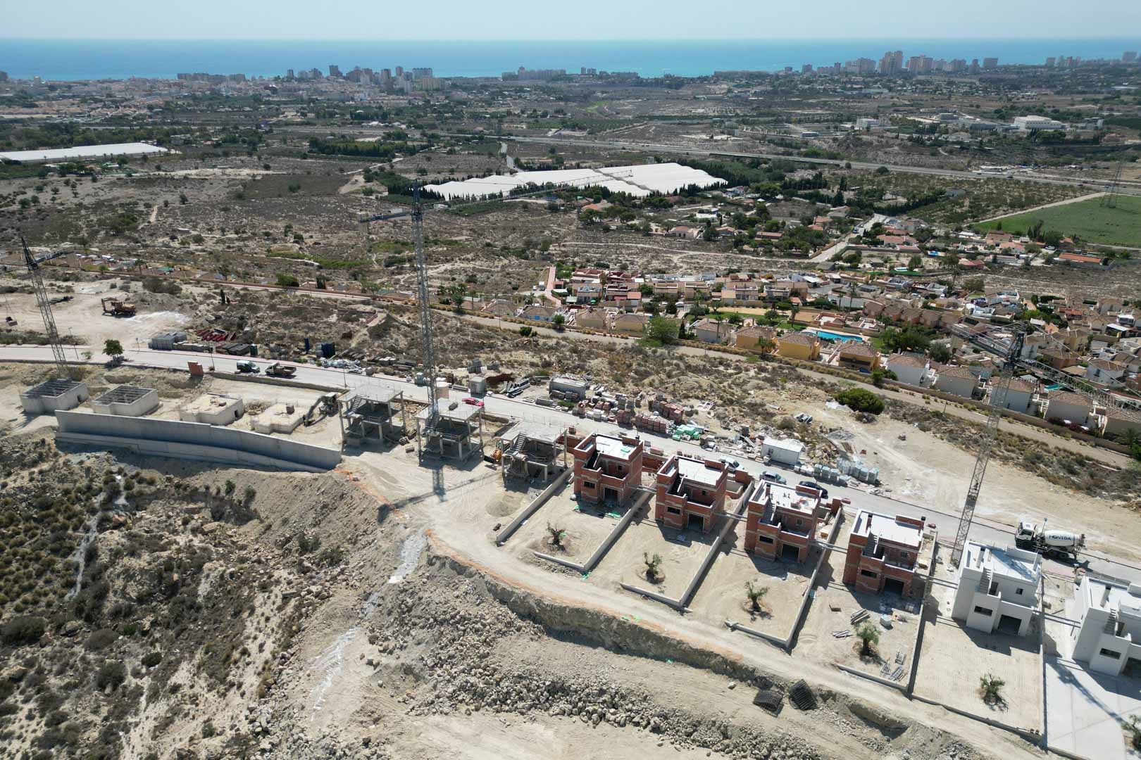 Vista aérea del desarrollo en construcción sobre una colina, mostrando las estructuras de las villas y vistas panorámicas hacia el mar Mediterráneo y la costa.
