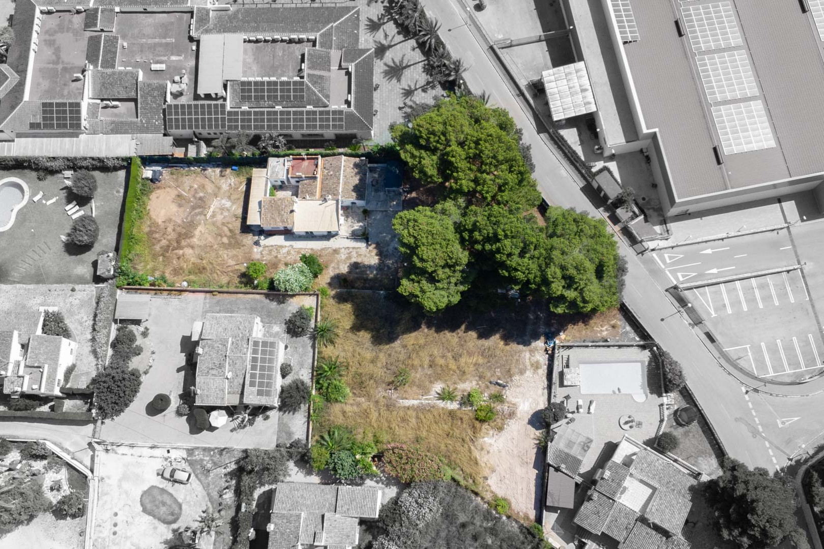 Vista aérea cenital de la parcela de 2.600 m² que muestra la vivienda existente, la zona arbolada con pinos maduros y su proximidad a servicios urbanos en Jávea.