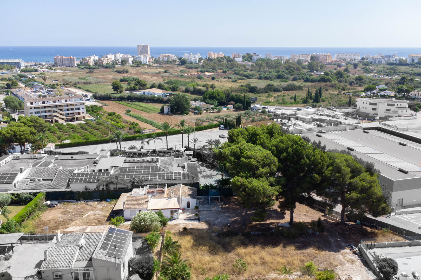 Vista aérea de la parcela de 2.600 m² en Jávea, mostrando la villa actual, pinos maduros y la cercanía al mar Mediterráneo y servicios urbanos.