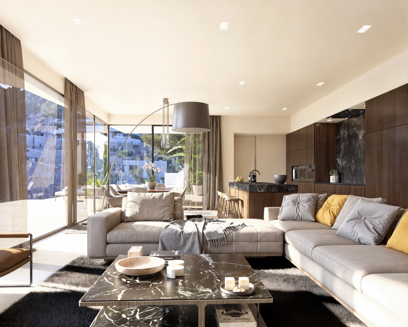 Salón de planta abierta con sofá modular, mesa de centro de mármol negro y cocina de diseño integrada con armarios de madera oscura y encimeras de piedra.