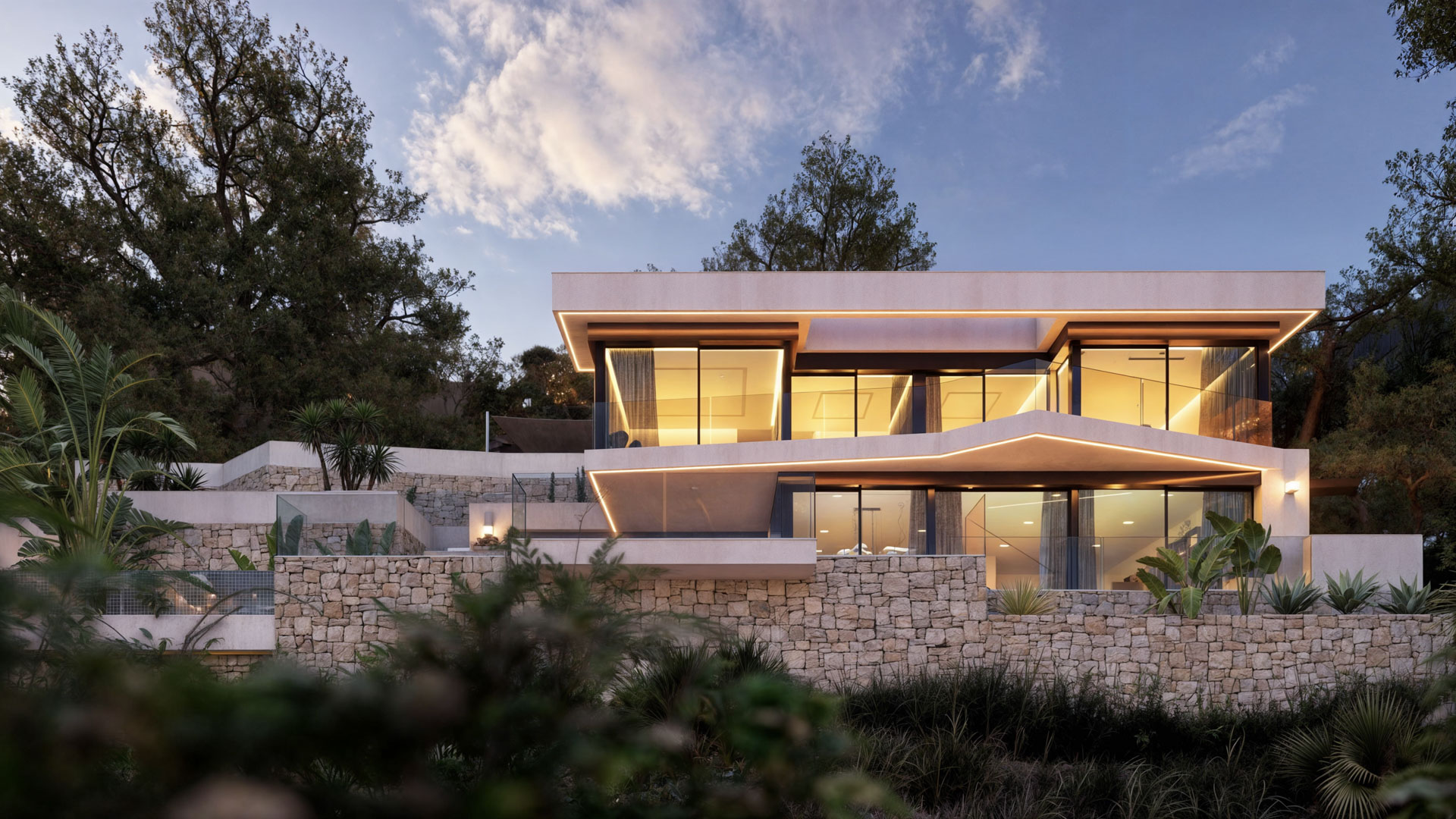 Vista exterior de la villa multinivel con muros de piedra natural, iluminación LED integrada y amplias fachadas acristaladas integradas en el terreno inclinado.