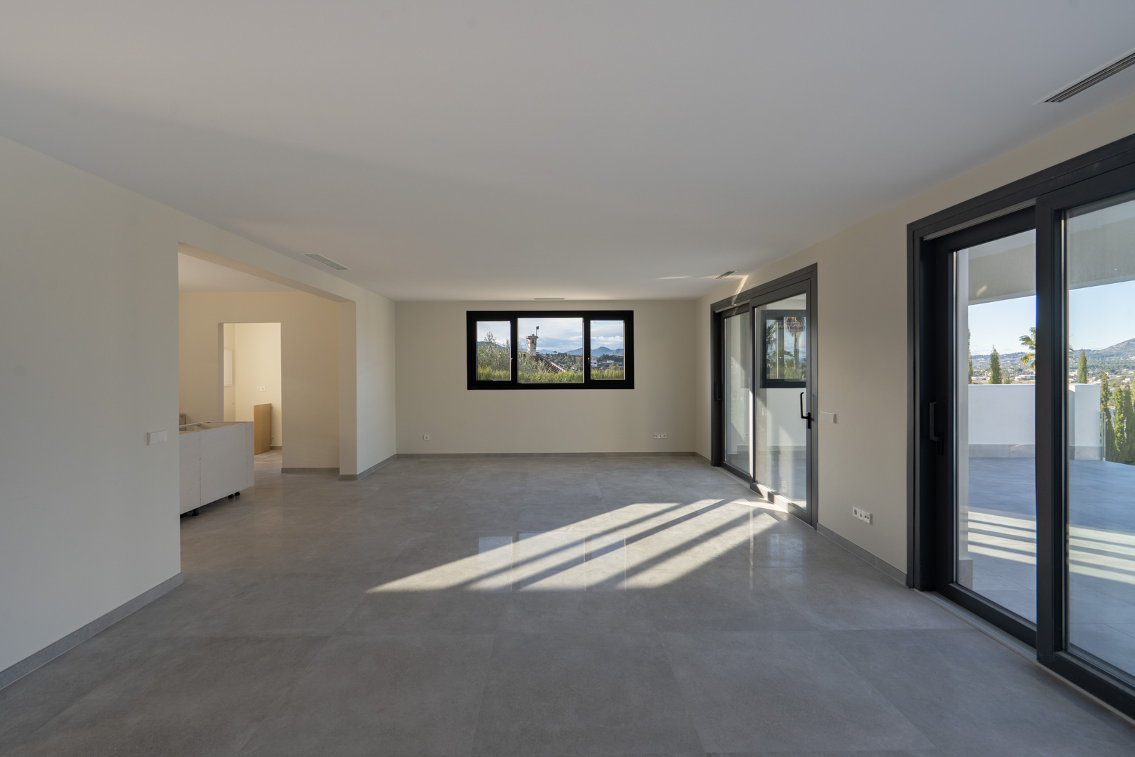 Amplio salón con suelo de gres, ventanal panorámico y acceso a la terraza en Jávea.