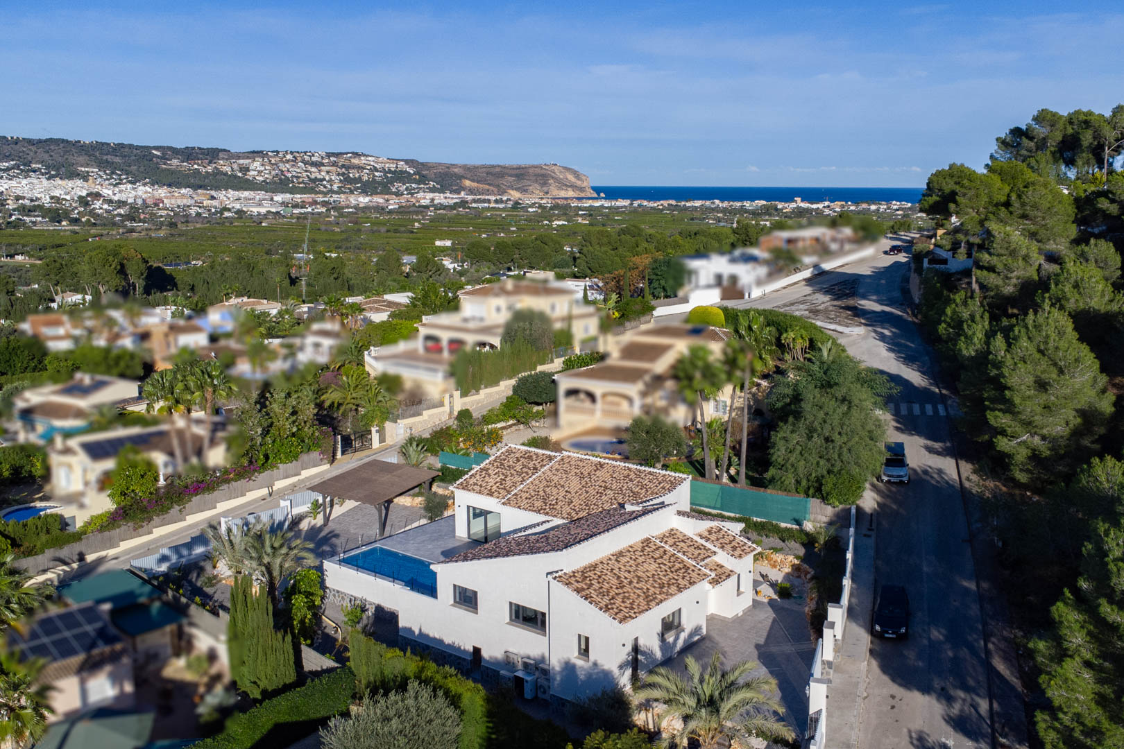 Vista aérea de villa moderna con piscina en Jávea, rodeada de jardines y con vistas al mar.