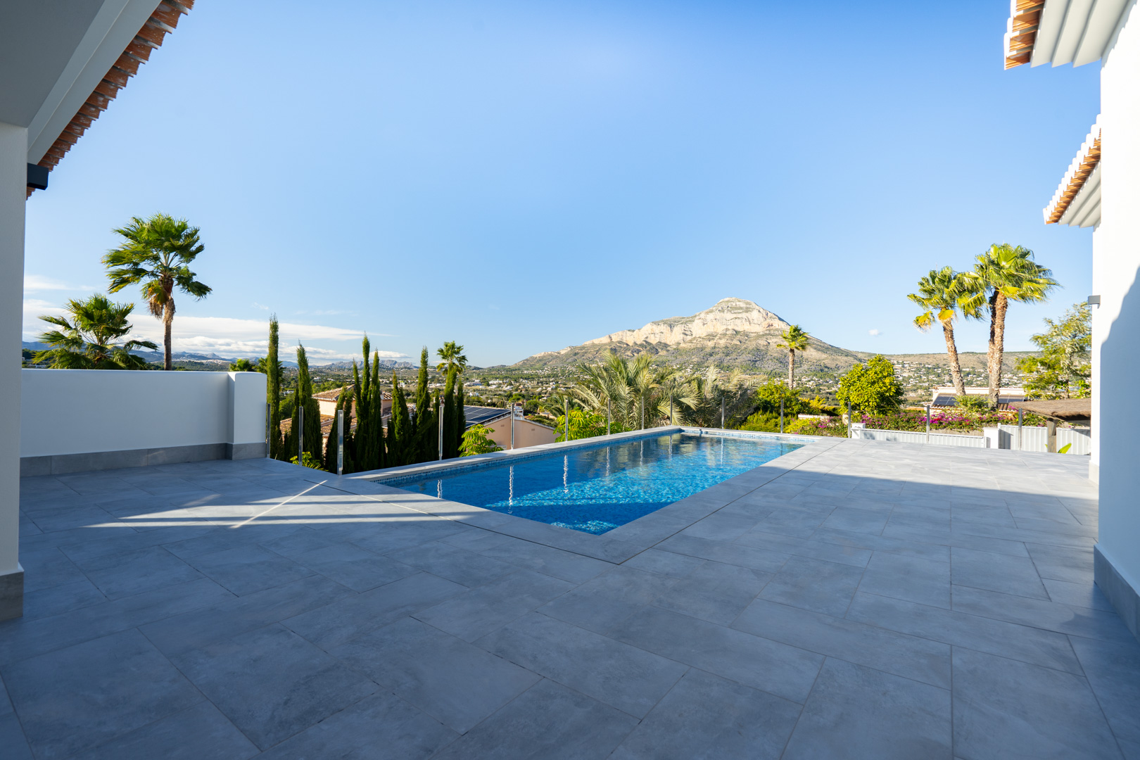 Vista de la piscina privada con baldosas grises y paisaje montañoso en Jávea.