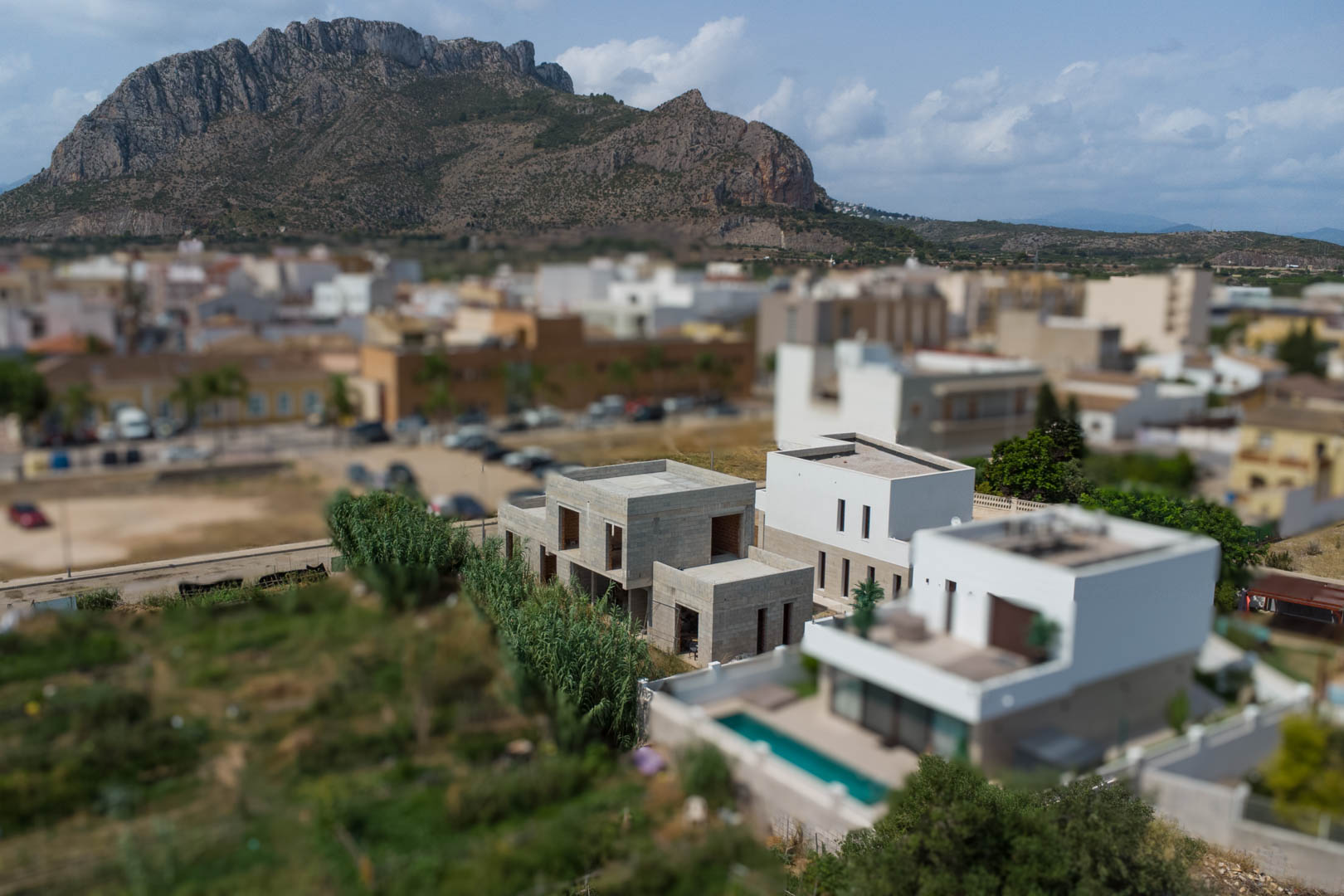 Vista aérea de tres villas modernas en distintas fases de obra en El Vergel, con la montaña Segaria al fondo y un entorno residencial consolidado.
