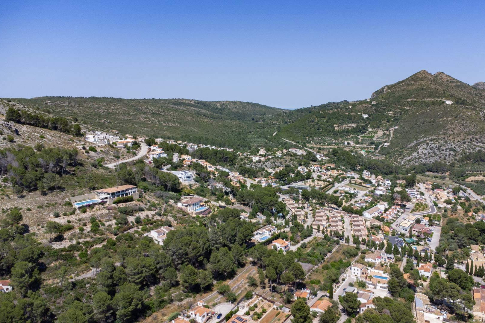 Vista aérea panorámica del Residencial VALL DE POP en Alcalalí, mostrando la integración de las viviendas en la ladera del valle de Jalón rodeadas de naturaleza mediterránea.