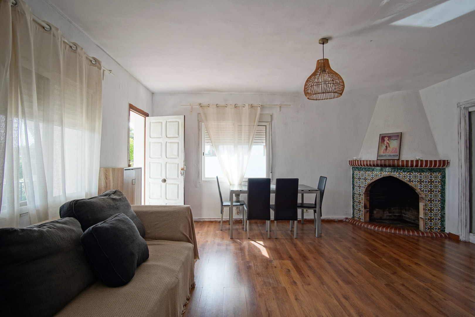 Salón comedor con chimenea de azulejos y mobiliario funcional.
