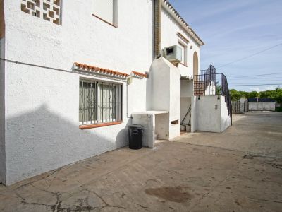 Exterior de la casa con barbacoa de obra y acceso a la planta superior por escalera.