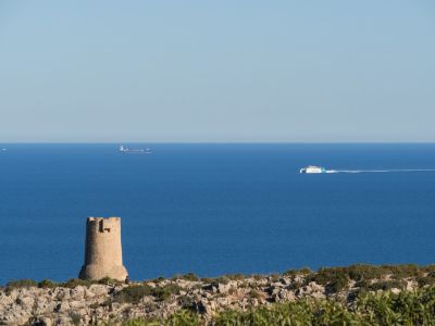 Vista del mar Mediterráneo desde Las Rotas con torre de piedra y barcos en el horizonte.