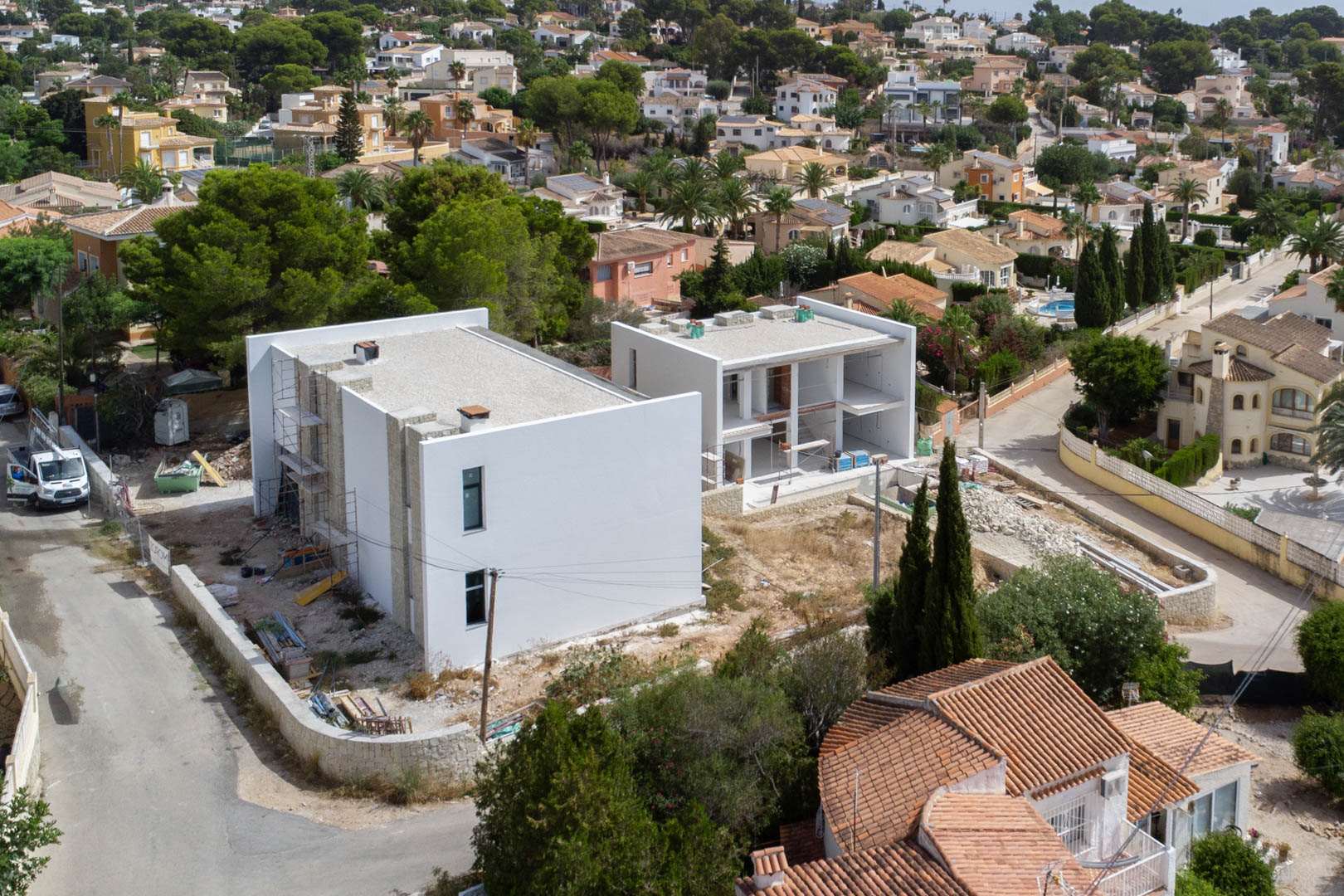 Vista aérea de la fase de construcción de las villas, mostrando la estructura moderna con muros blancos y detalles en piedra natural en la zona de La Merced.