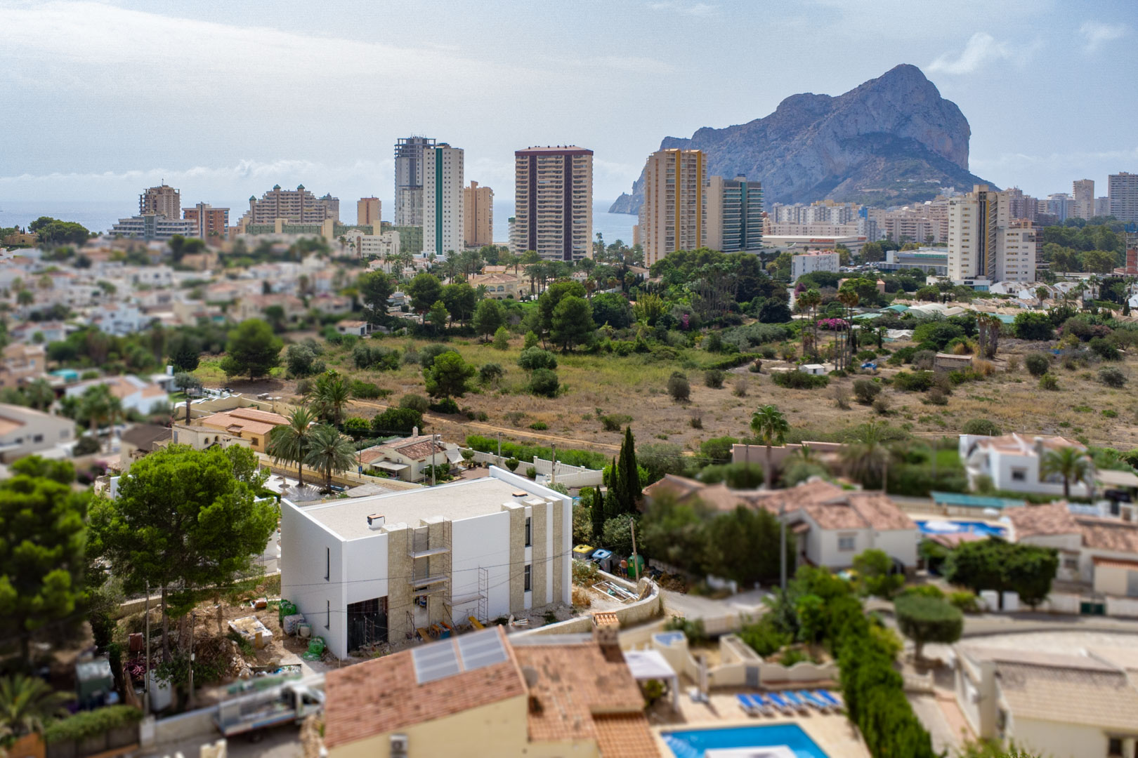 Vista aérea de la villa en construcción con fachada blanca y piedra, mostrando su proximidad al mar y las vistas panorámicas al Peñón de Ifach en Calpe.